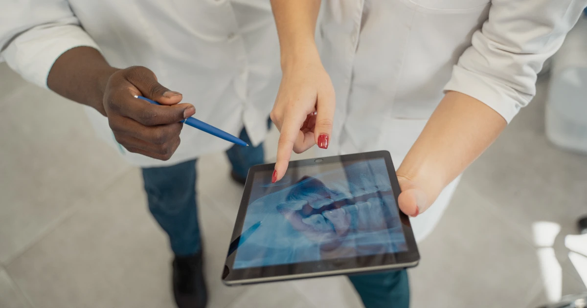 Two medical professionals conferring over patient xrays on tablet device.