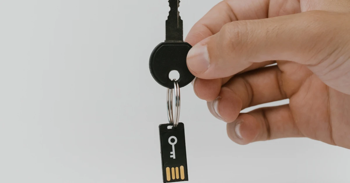Hand holding physical key attached to digital key fob.