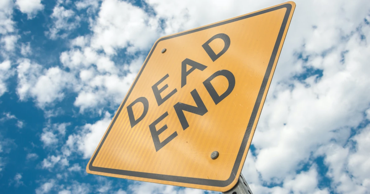 Yellow diamond "Dead End" road sign viewed from below, with blow sky and clouds in background.